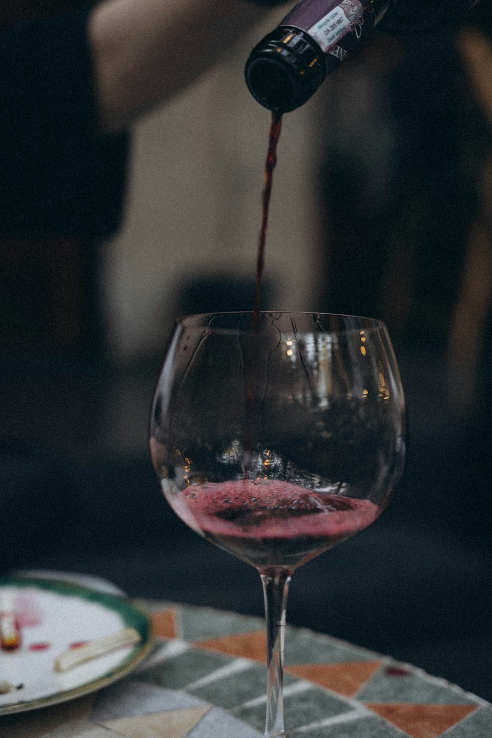 Vino rosso versato in un bicchiere trasparente su un tavolo.