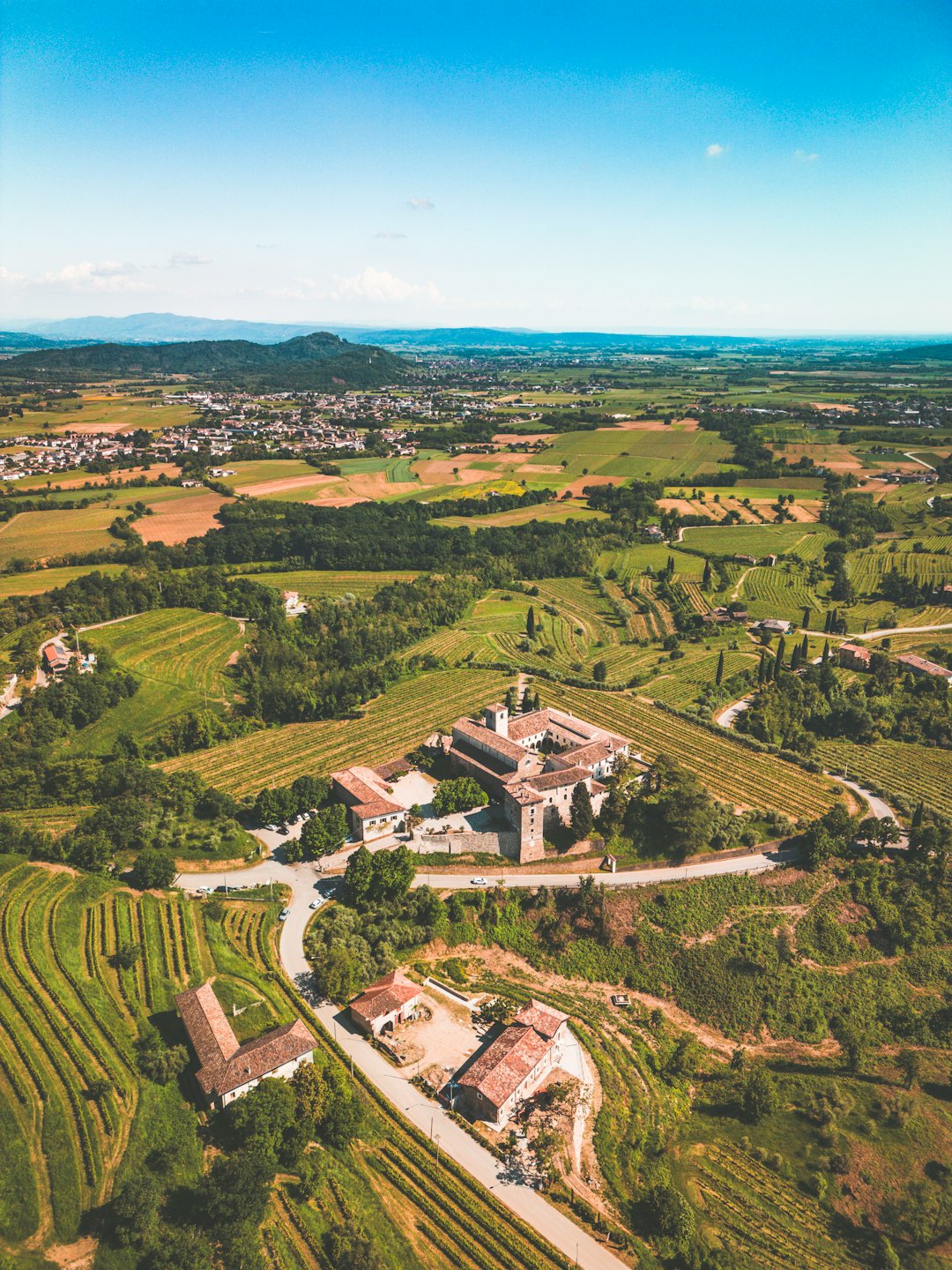 Antichi edifici in pietra con tetti rossi tra vigneti terrazzati verdi.