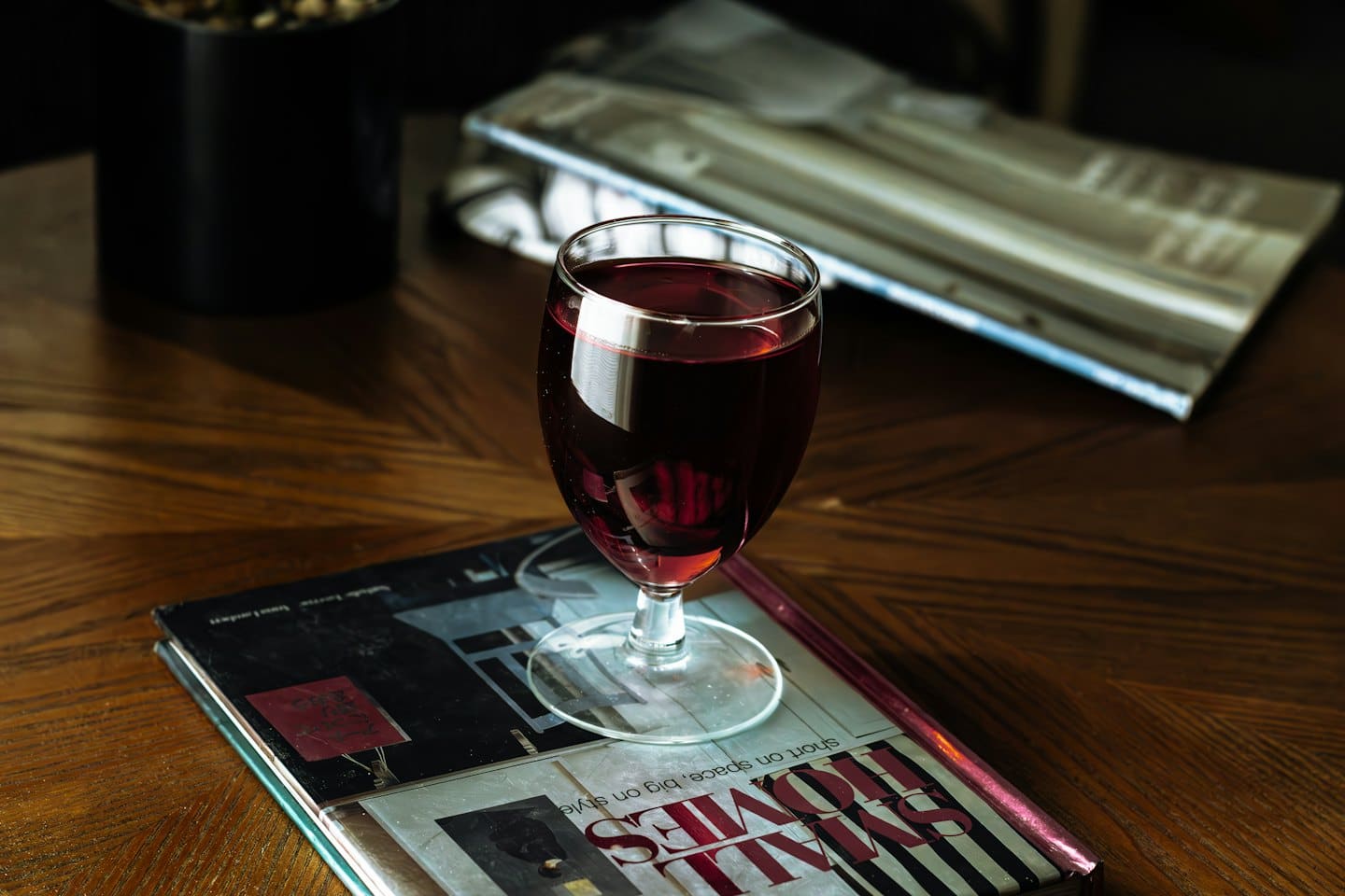 Un bicchiere di vino rosso su una rivista aperta.