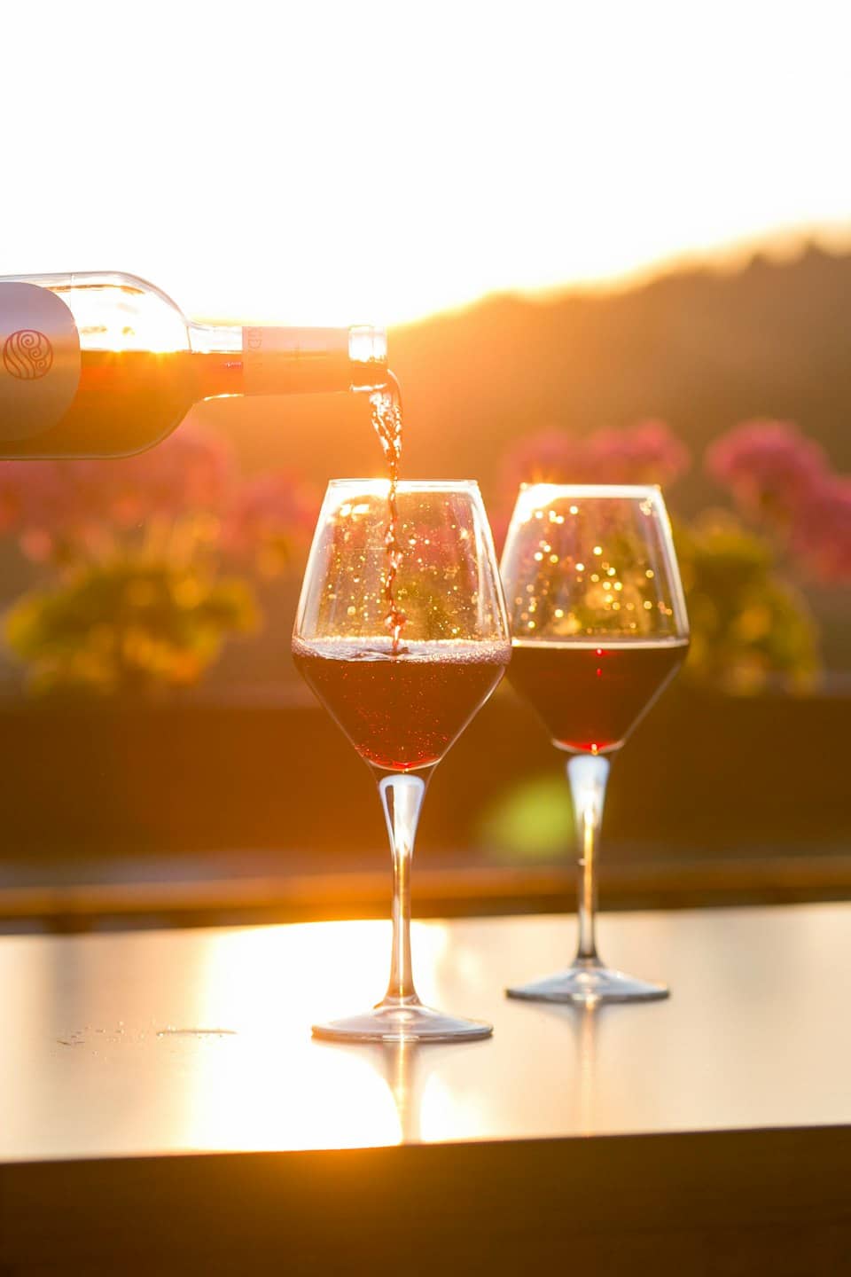 Vino rosso versato in un calice di cristallo al tramonto.